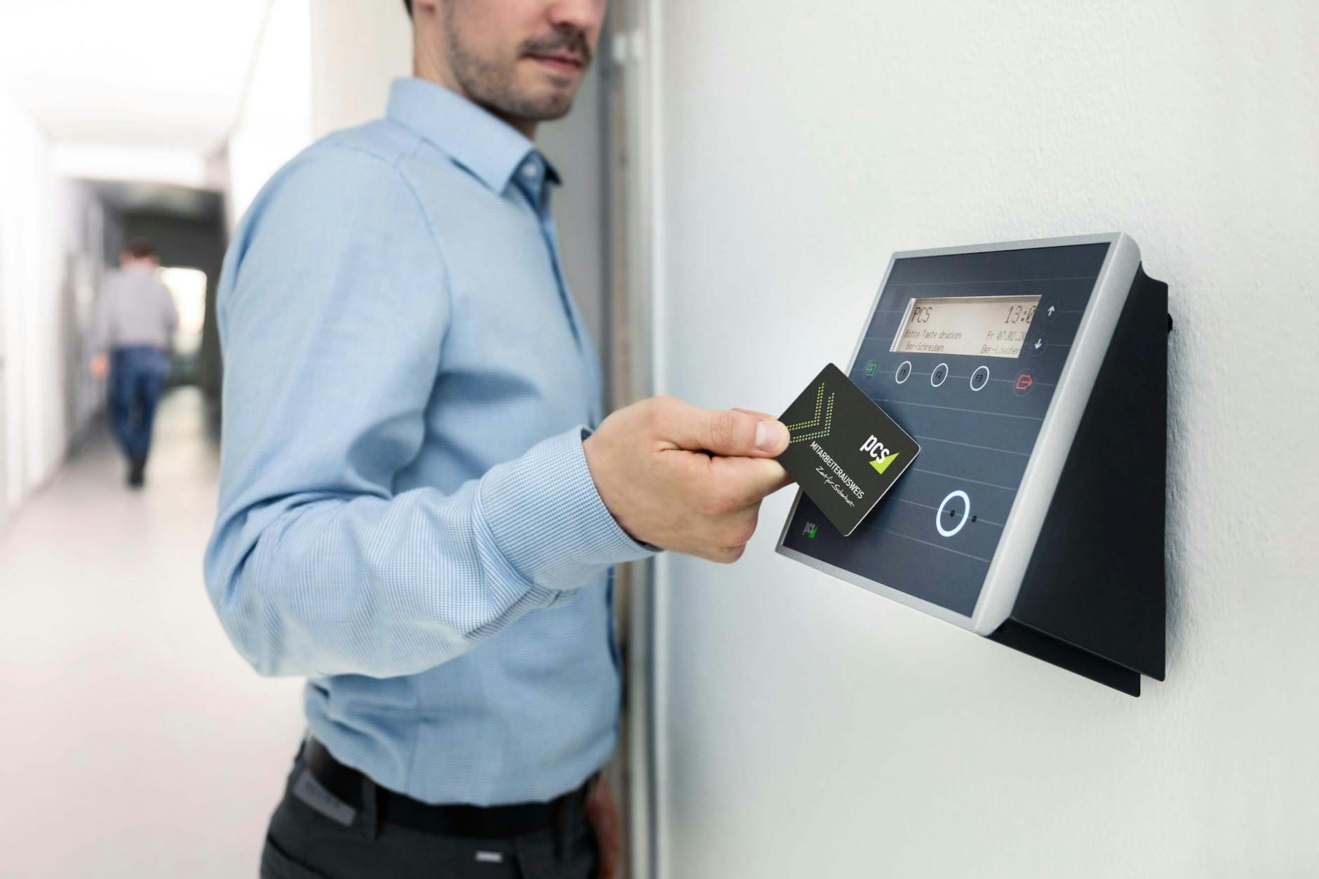 Pracownik przykłada kartę RFID do czytnika przy wejściu do biura