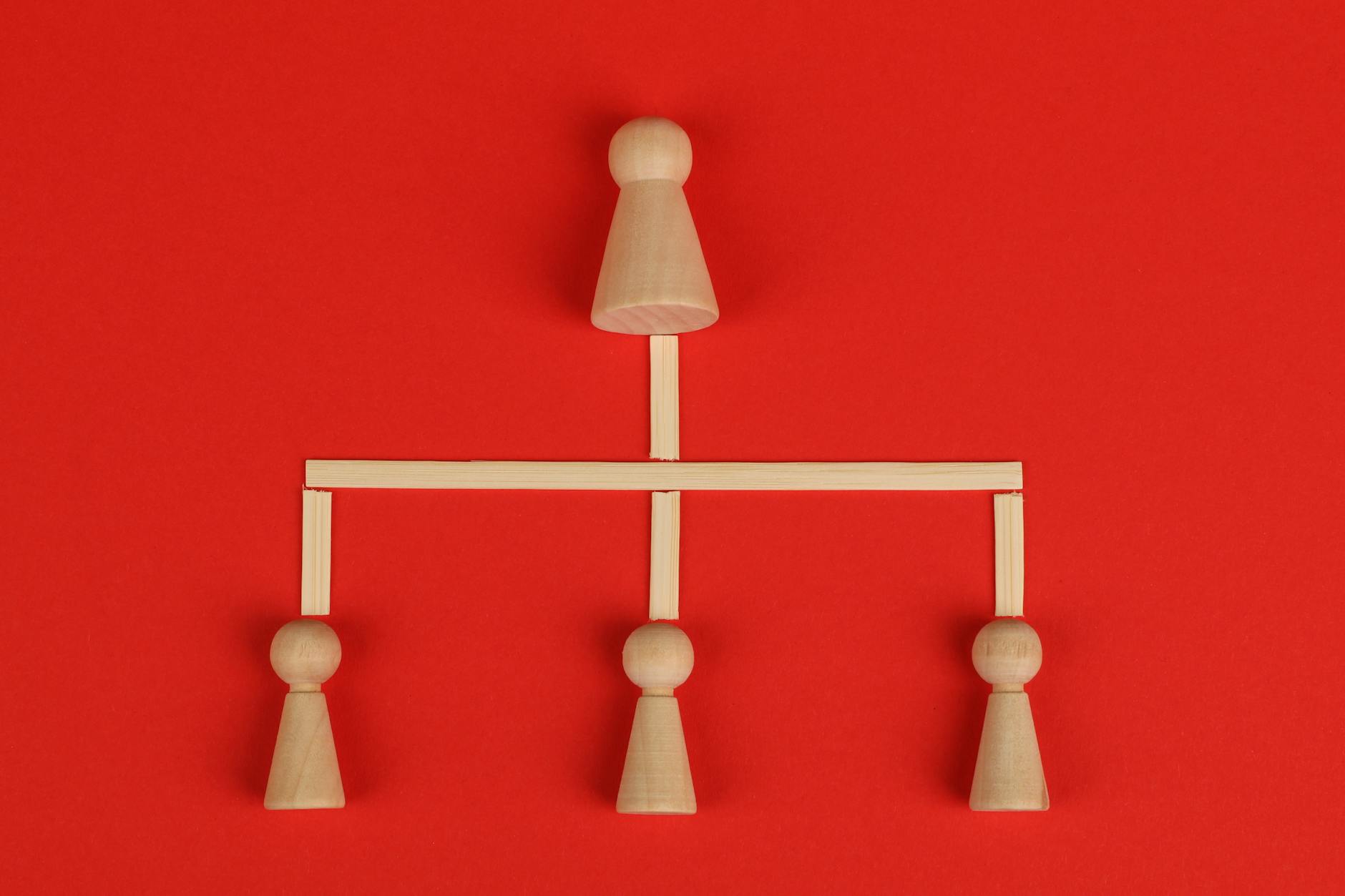 Drewniane pionki ustawione hierarchicznie na czerwonym tle