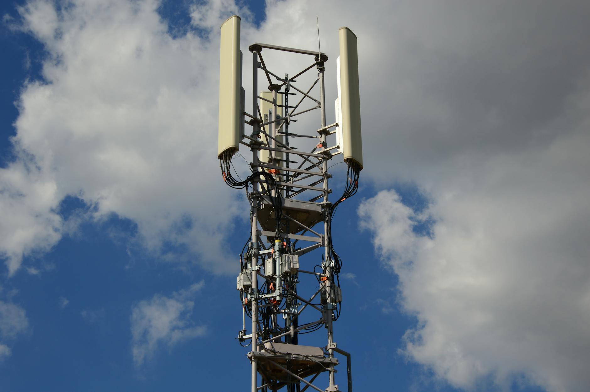 Nowoczesna wieża 5G z antenami na tle niebieskiego nieba z chmurami