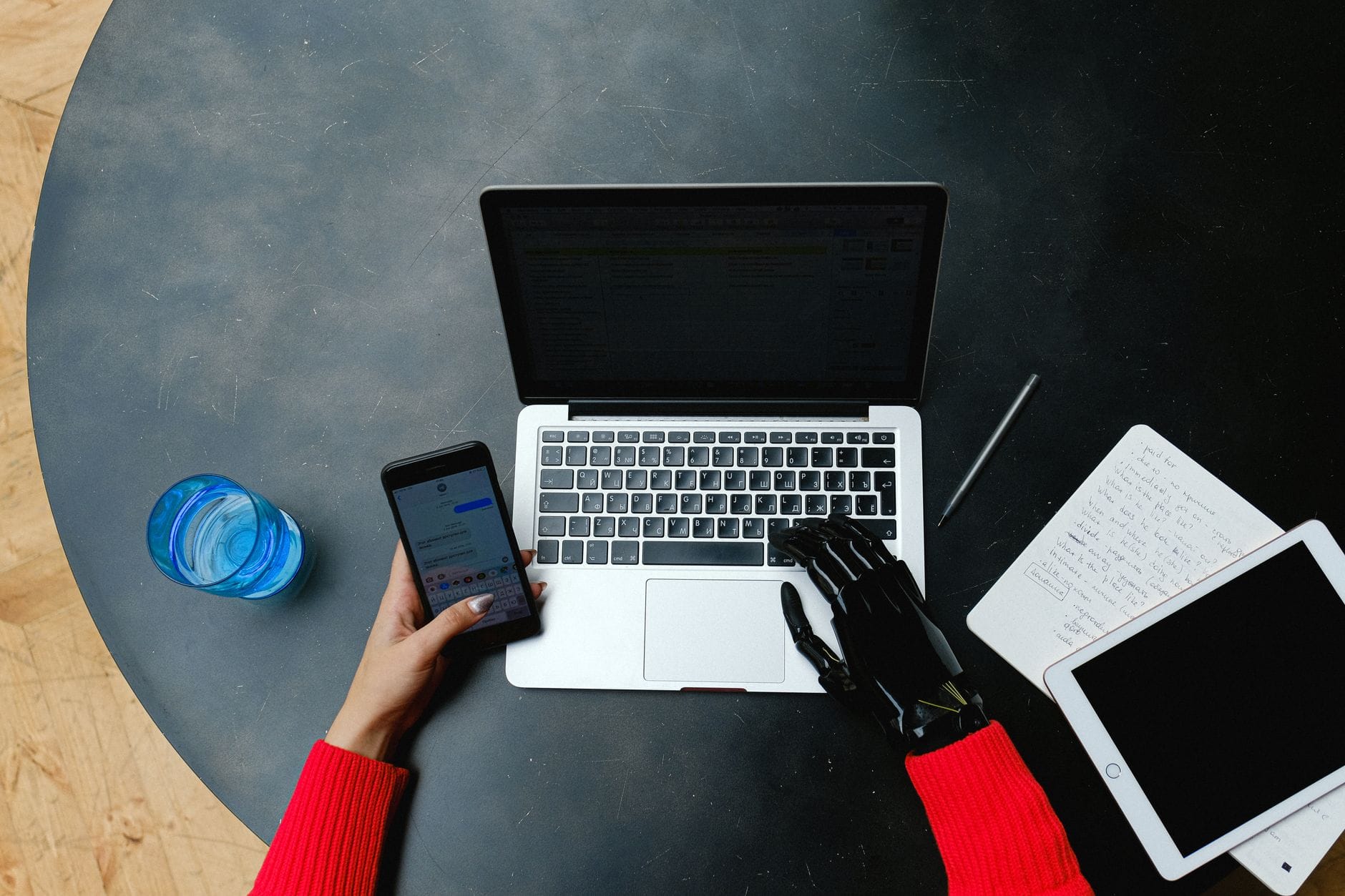 Osoba z protezą dłoni korzysta z laptopa, smartfona i tabletu