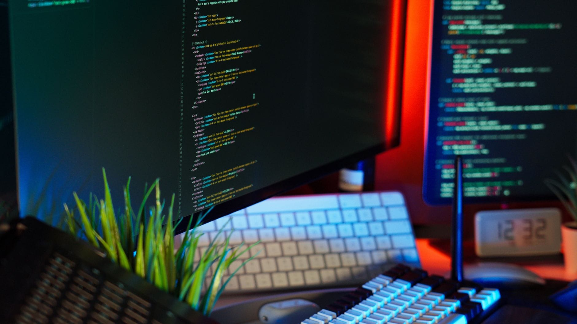 Stanowisko programisty z monitorami pełnymi kodu i akcesoriami komputerowymi