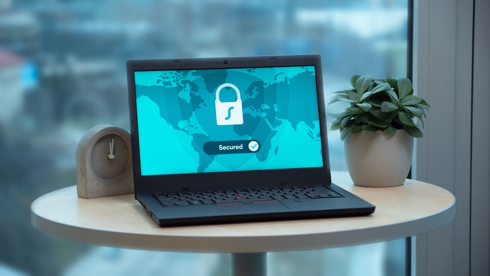 Ostatnie łatki bezpieczeństwa Windows i Linux: co musisz zaktualizować teraz Laptop z ikoną kłódki na ekranie na biurku obok rośliny i zegara