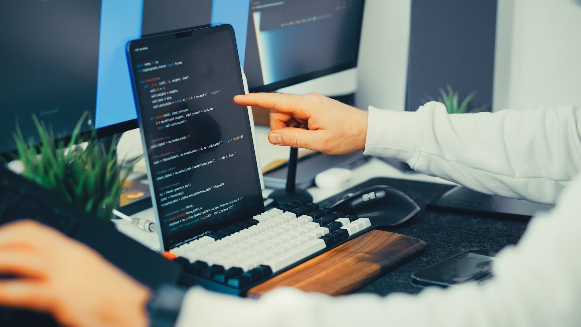 Programista analizujący kod na laptopie i monitorze w biurze