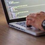 Jak zredukować zużycie RAM przez skrypty Python przetwarzające duże pliki CSV i JSON Osoba programująca w Pythonie na laptopie z widocznym ekranem